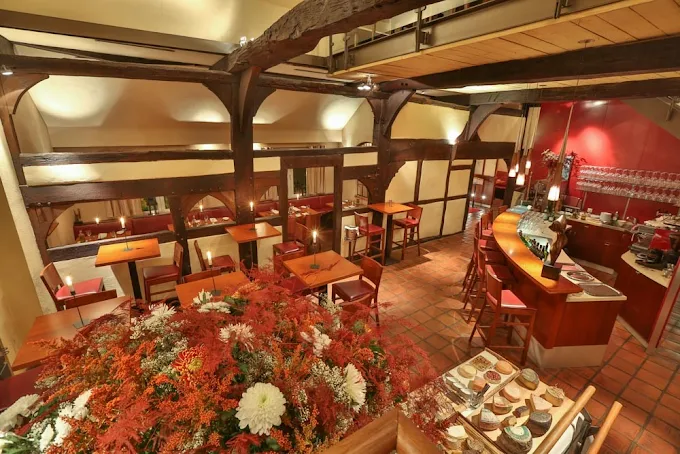 Warmer Gastraum mit Holzbalken, Blumenarrangement und Käsebuffet